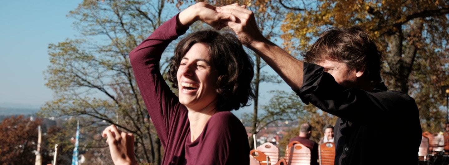 CPES5721_1440x530_bearbeitet_skaliert Tanzpaar im Biergarten, sie dreht unter seinem Arm durch und lacht dabei von Herzen